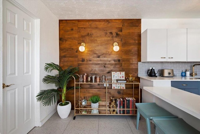 interior space with white cabinets, decorative backsplash, and wooden walls