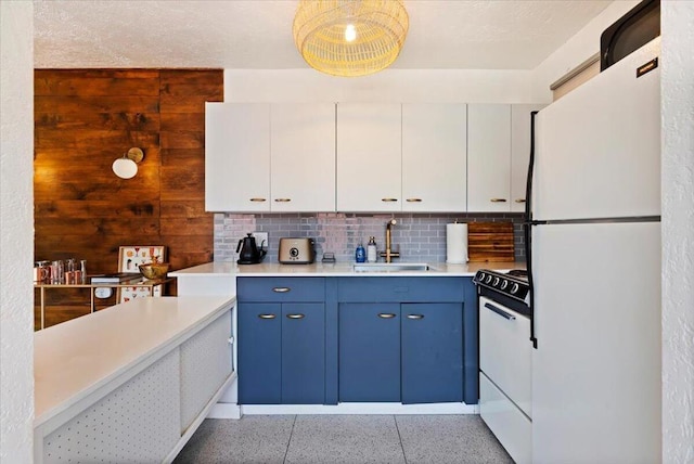 kitchen featuring electric range oven, white cabinets, white fridge, sink, and blue cabinets