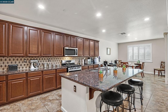 kitchen with sink, stainless steel appliances, a breakfast bar, and a kitchen island with sink