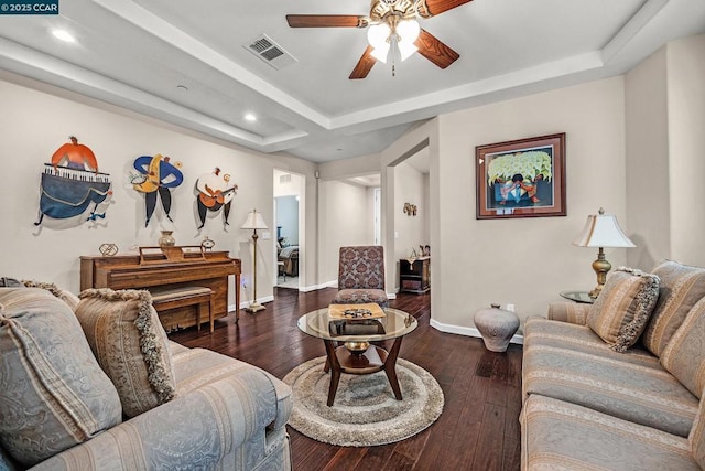 living room featuring ceiling fan, a raised ceiling, and dark hardwood / wood-style floors