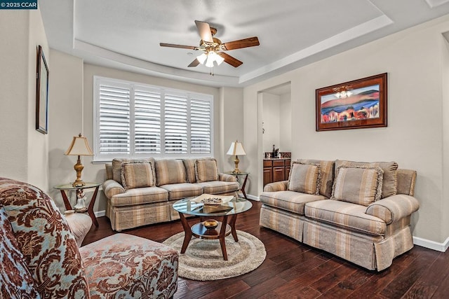 living room featuring ceiling fan, dark hardwood / wood-style floors, and a tray ceiling