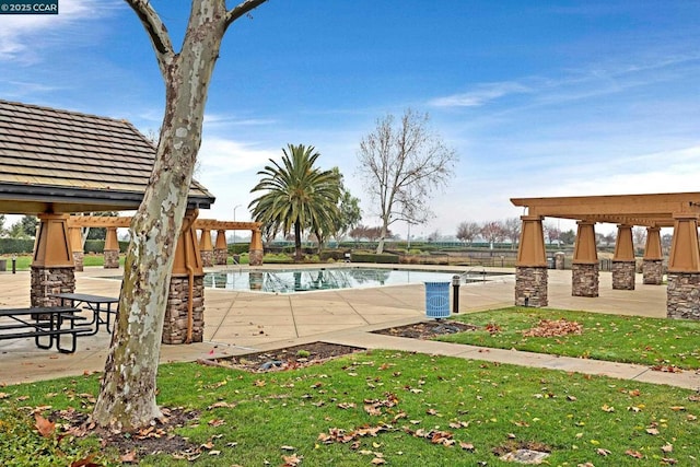 view of pool with a patio area, a lawn, and a water view