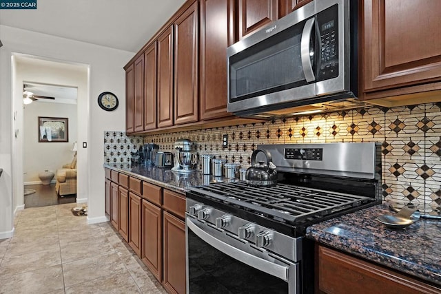 kitchen with tasteful backsplash, ceiling fan, stainless steel appliances, light tile patterned floors, and dark stone counters