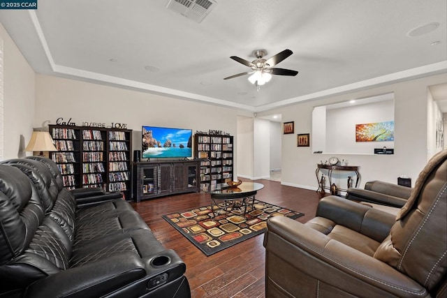 living room with ceiling fan, dark hardwood / wood-style flooring, and a raised ceiling