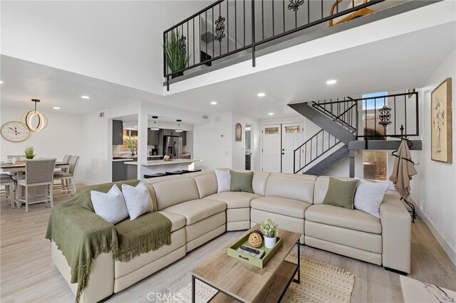 living room with a wealth of natural light, light hardwood / wood-style flooring, and a high ceiling