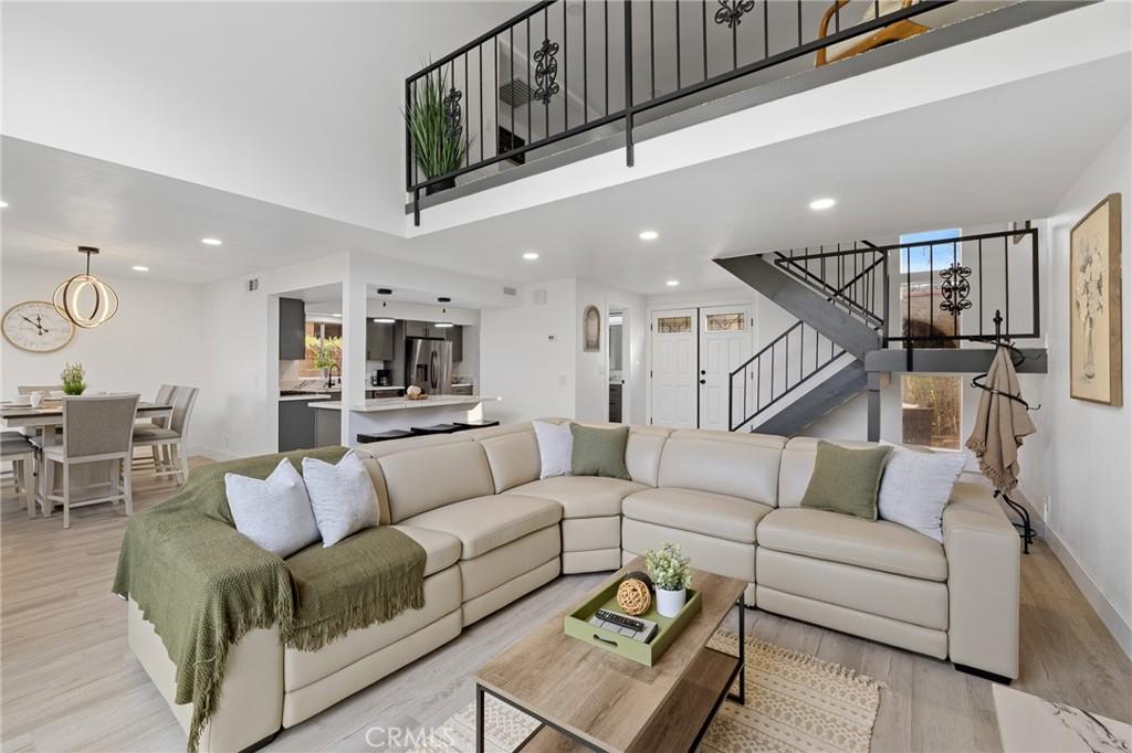 living room featuring light hardwood / wood-style floors, a towering ceiling, and plenty of natural light