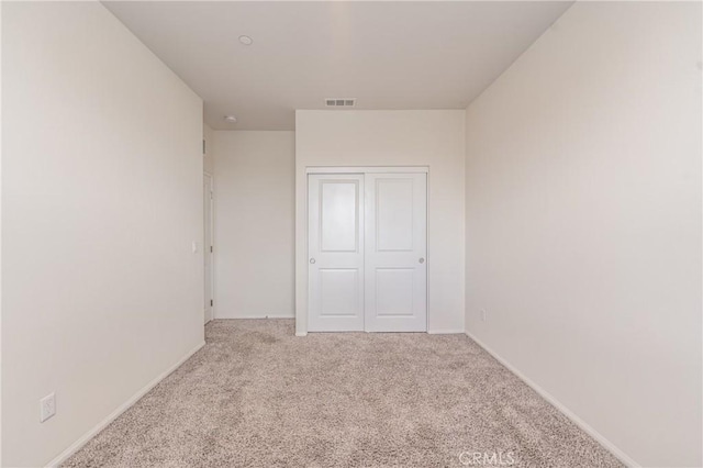 unfurnished bedroom featuring a closet and light carpet