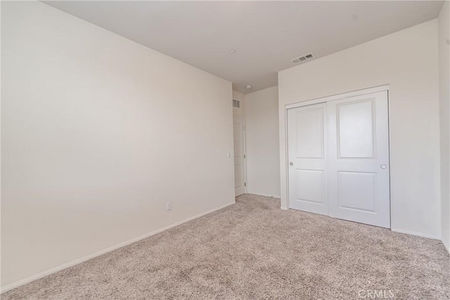 unfurnished bedroom featuring light carpet and a closet