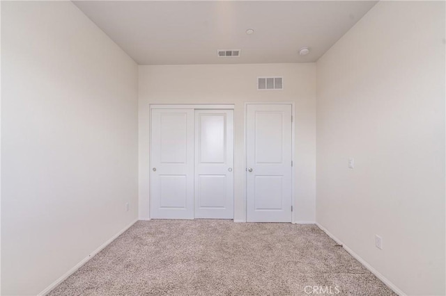 unfurnished bedroom featuring light colored carpet and a closet