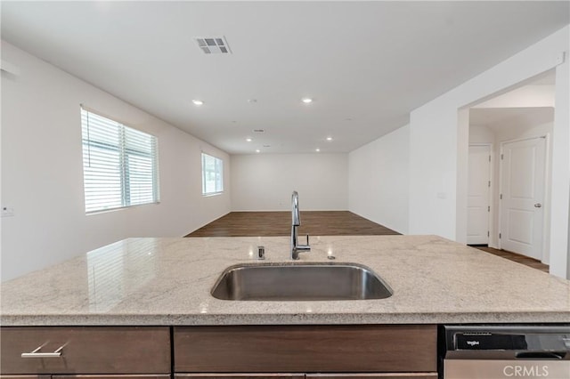 kitchen featuring light stone counters, stainless steel dishwasher, and sink