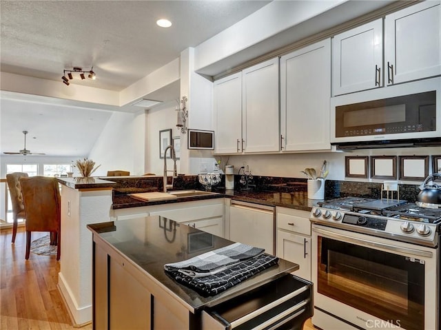 kitchen with ceiling fan, dishwasher, sink, stainless steel range with gas cooktop, and white cabinetry