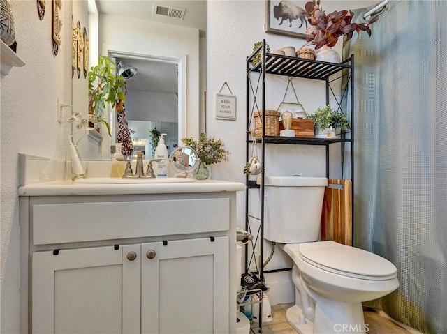 bathroom with toilet, vanity, and curtained shower