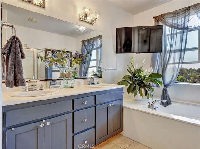 bathroom with a healthy amount of sunlight, tile patterned flooring, vanity, and a bath