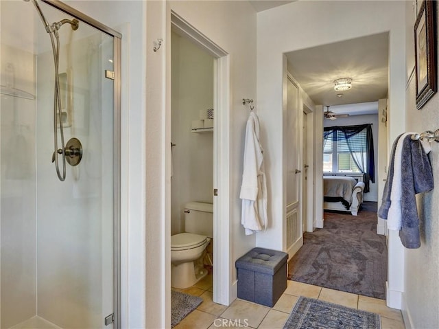 bathroom featuring toilet, ceiling fan, tile patterned flooring, and a shower with door