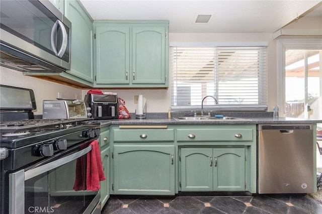 kitchen with appliances with stainless steel finishes, sink, and green cabinets