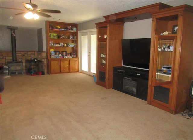 living area with light carpet, ceiling fan, and a wood stove