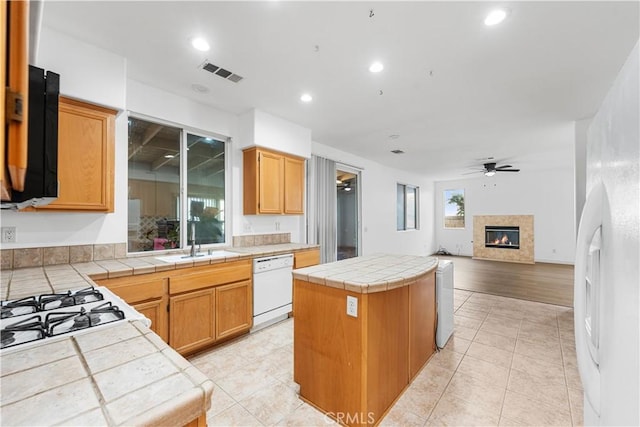 kitchen featuring a center island, tile counters, ceiling fan, sink, and white dishwasher