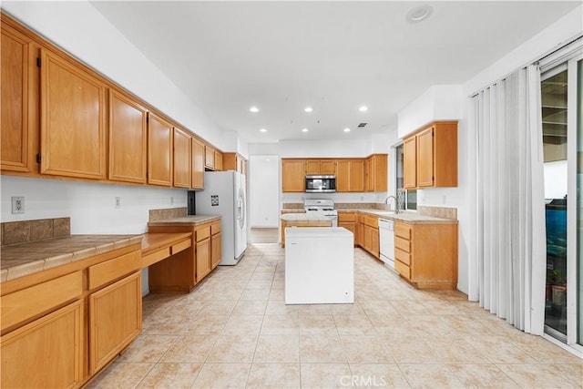 kitchen with a wealth of natural light, white appliances, tile counters, and a kitchen island