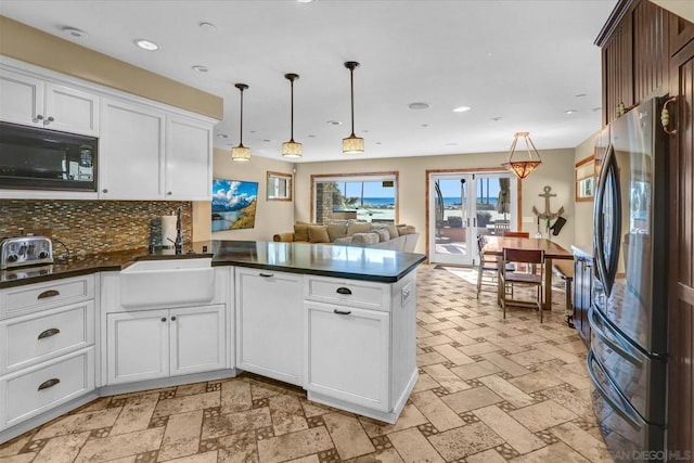 kitchen featuring refrigerator, tasteful backsplash, black microwave, kitchen peninsula, and pendant lighting