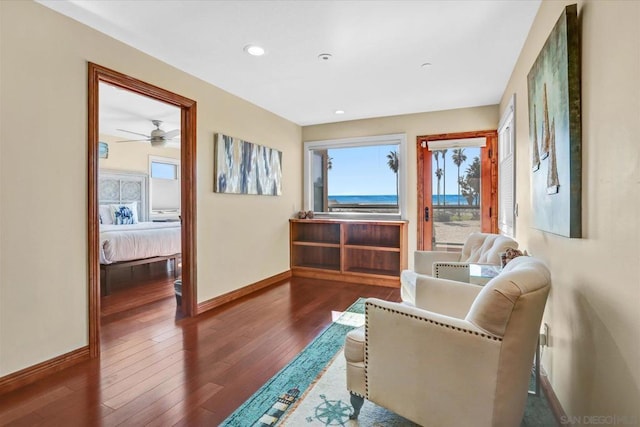 living area with a water view, ceiling fan, and dark hardwood / wood-style flooring