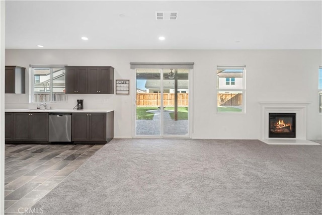 unfurnished living room with sink, light carpet, and a healthy amount of sunlight