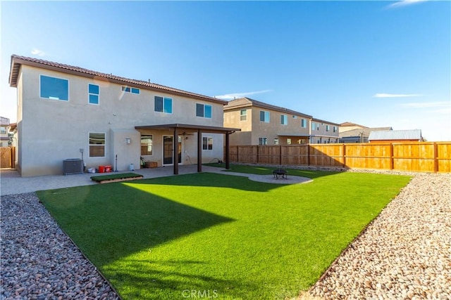 rear view of property featuring a lawn, central AC unit, and a patio