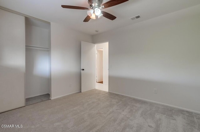 unfurnished bedroom featuring light colored carpet, ceiling fan, and a closet