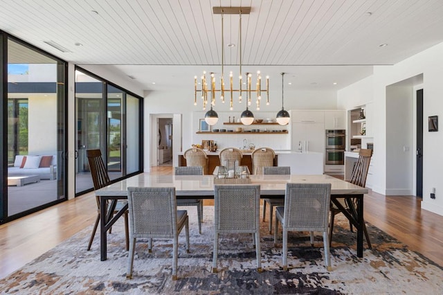 dining room with light hardwood / wood-style flooring, an inviting chandelier, wood ceiling, and expansive windows