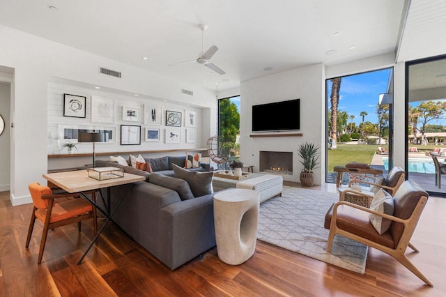 living room with ceiling fan, a fireplace, and wood-type flooring