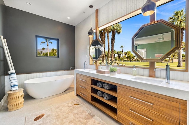 bathroom featuring vanity, tile patterned flooring, a healthy amount of sunlight, and a bath