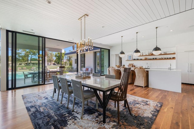 dining area featuring light wood-type flooring, wood ceiling, expansive windows, and sink