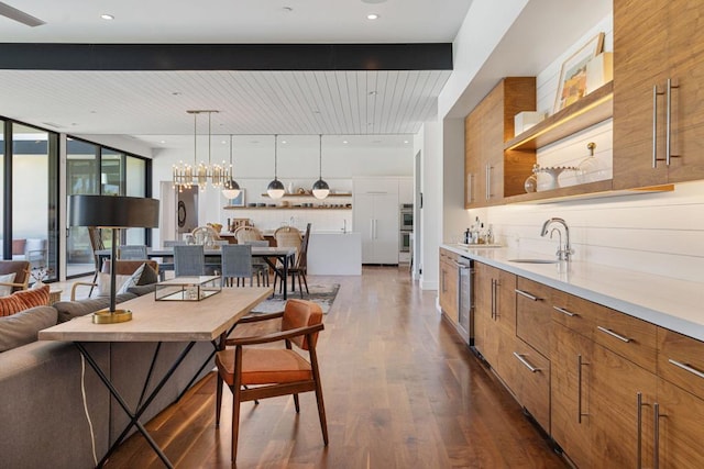 kitchen with sink, hanging light fixtures, dark hardwood / wood-style floors, expansive windows, and a breakfast bar area