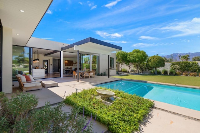 view of pool with a lawn, a patio area, and a mountain view