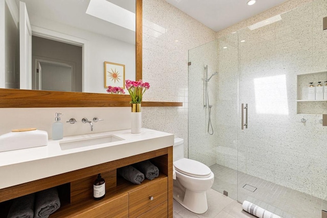 bathroom with toilet, vanity, tile walls, tile patterned floors, and a shower with shower door