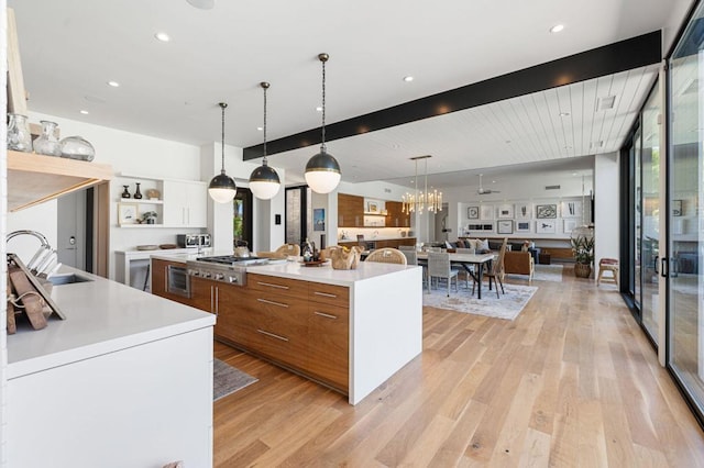 kitchen with stainless steel gas stovetop, white cabinetry, a large island, pendant lighting, and sink