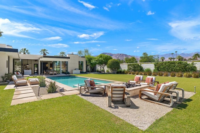 view of swimming pool featuring a mountain view, a patio area, an outdoor fire pit, and a lawn