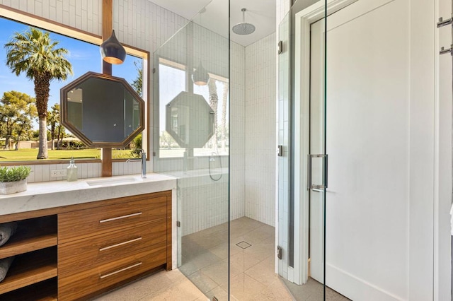 bathroom featuring vanity, a tile shower, and a healthy amount of sunlight