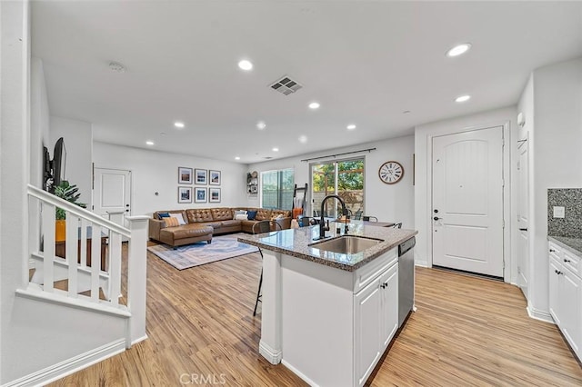 kitchen with white cabinets, dishwasher, sink, and a center island with sink