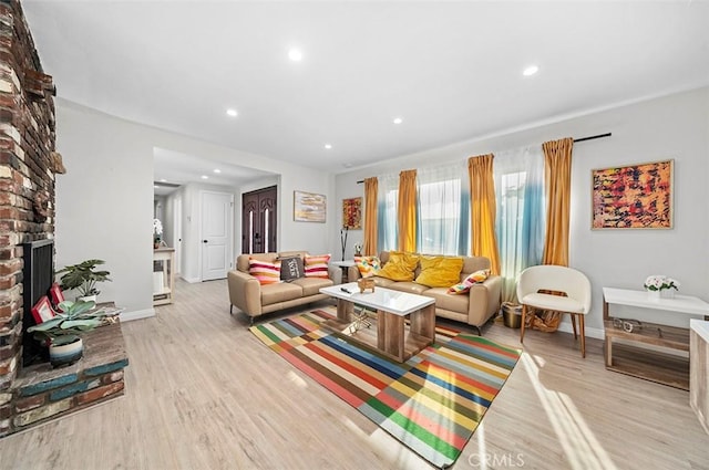 living room featuring a brick fireplace and light hardwood / wood-style floors