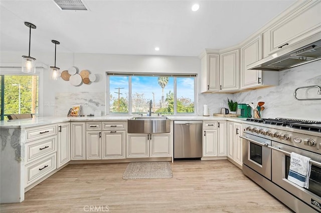 kitchen featuring decorative backsplash, sink, stainless steel appliances, and wall chimney exhaust hood