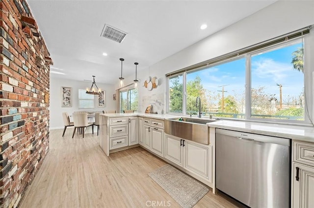 kitchen featuring light hardwood / wood-style floors, kitchen peninsula, hanging light fixtures, stainless steel dishwasher, and sink