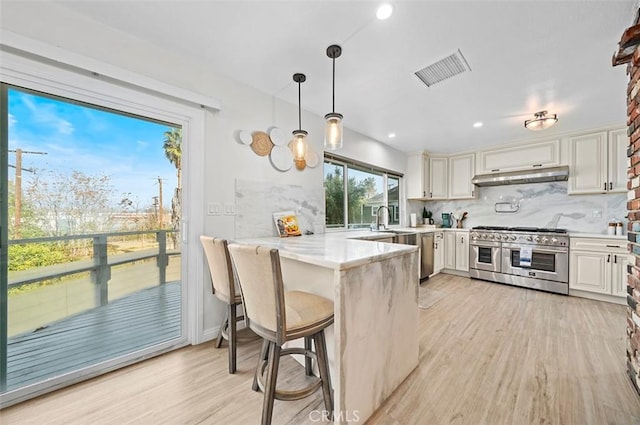 kitchen featuring light stone countertops, white cabinetry, double oven range, kitchen peninsula, and a breakfast bar