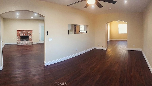 spare room with ceiling fan, a fireplace, and dark hardwood / wood-style flooring