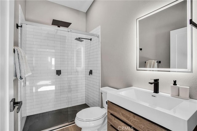 bathroom featuring toilet, vanity, and a shower with door