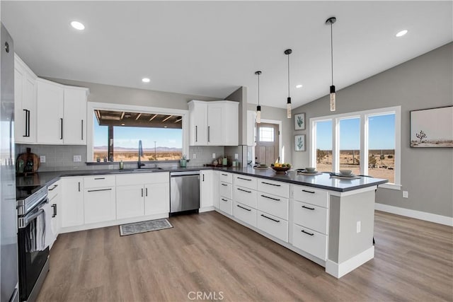 kitchen with white cabinetry, kitchen peninsula, appliances with stainless steel finishes, decorative light fixtures, and sink