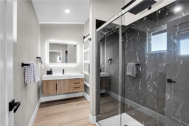 bathroom with a shower with shower door, hardwood / wood-style flooring, and vanity