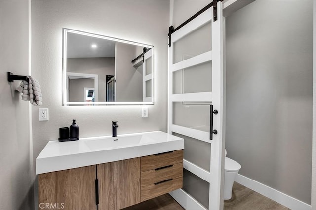 bathroom featuring wood-type flooring, toilet, and vanity