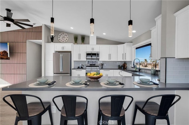 kitchen with vaulted ceiling, white cabinetry, stainless steel appliances, and backsplash