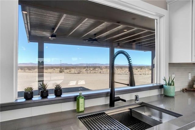 interior details with white cabinetry, decorative backsplash, a mountain view, and sink