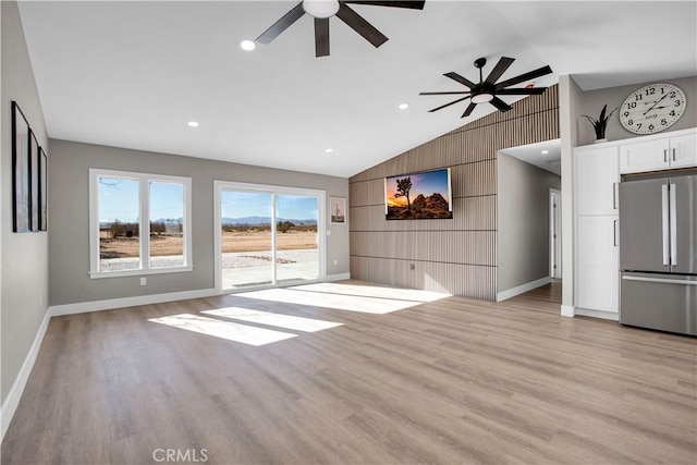 unfurnished living room with light wood-type flooring, ceiling fan, lofted ceiling, and wooden walls